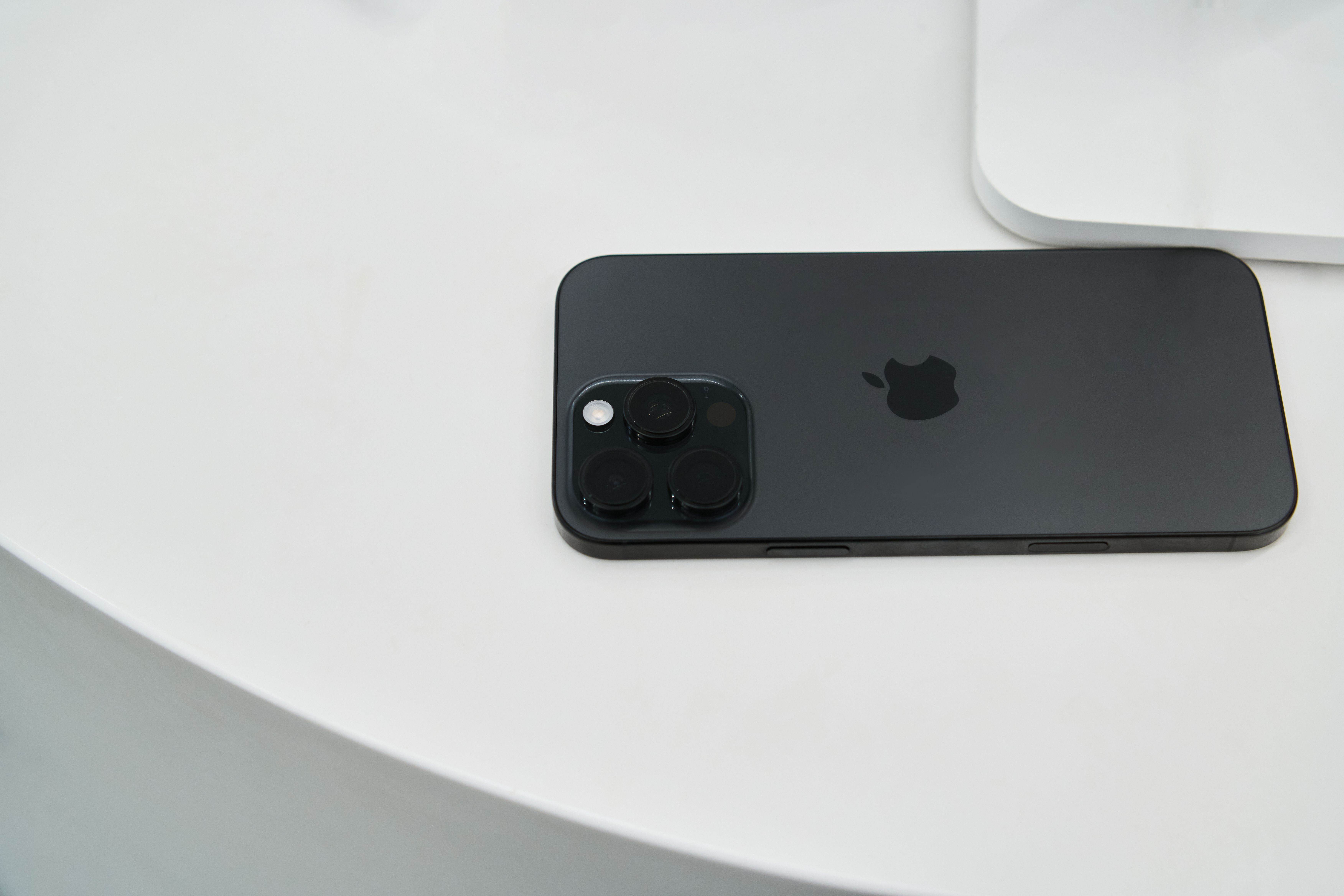 A sleek black smartphone with triple camera lenses on a modern white table.