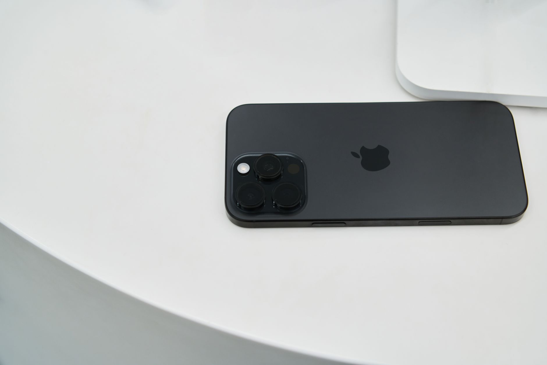 A sleek black smartphone with triple camera lenses on a modern white table.