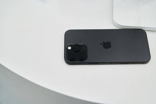 A sleek black smartphone with triple camera lenses on a modern white table.