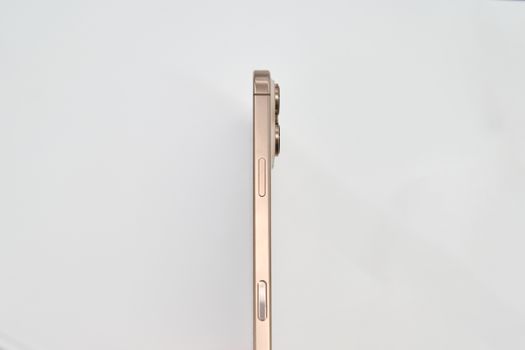 Minimalist side view of a gold smartphone on white background.