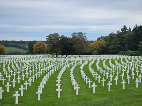 A peaceful cemetery with rows of white cross tombstones in Plombières, Belgium.