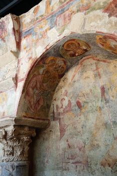 Intricate fresco depicting religious figures on a stone archway in an ancient setting.