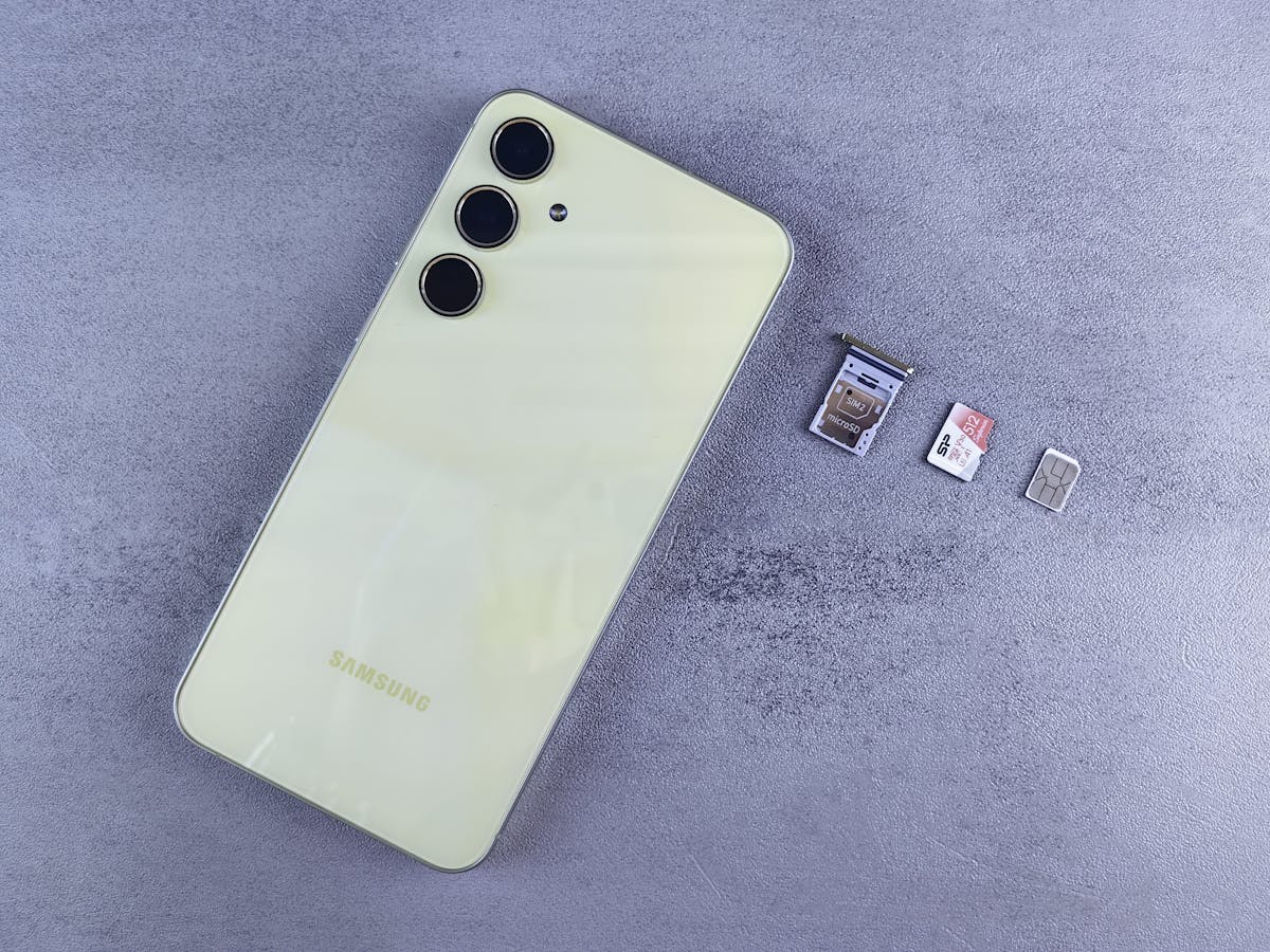 Smartphone giallo con vassoio SIM, nano SIM e scheda microSD su sfondo grigio
