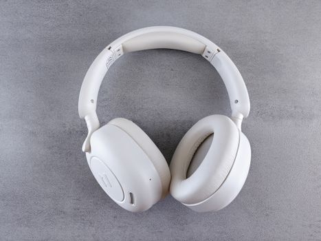 Close-up of sleek white wireless headphones on a textured gray surface. Ideal for audio enthusiasts.