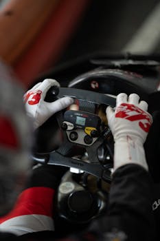 Close-up of a go-kart driver handling the steering wheel, focusing on race control buttons.