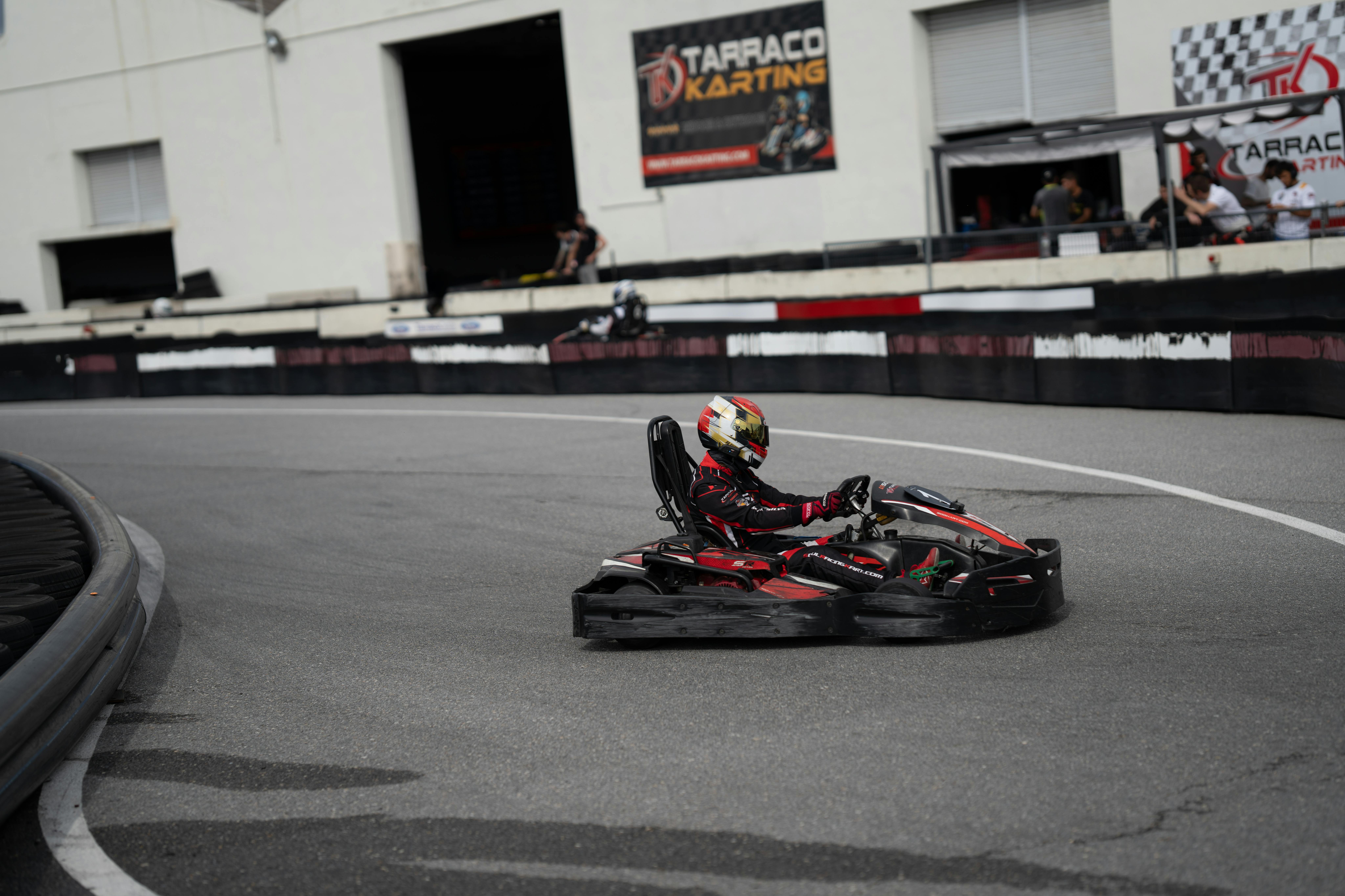 A go-kart racer wearing a helmet speeds on the track at Tarraco Karting