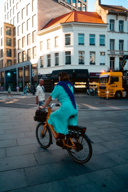 Free Woman riding a bike through sunny streets of Antwerp, Belgium. Stock Photo