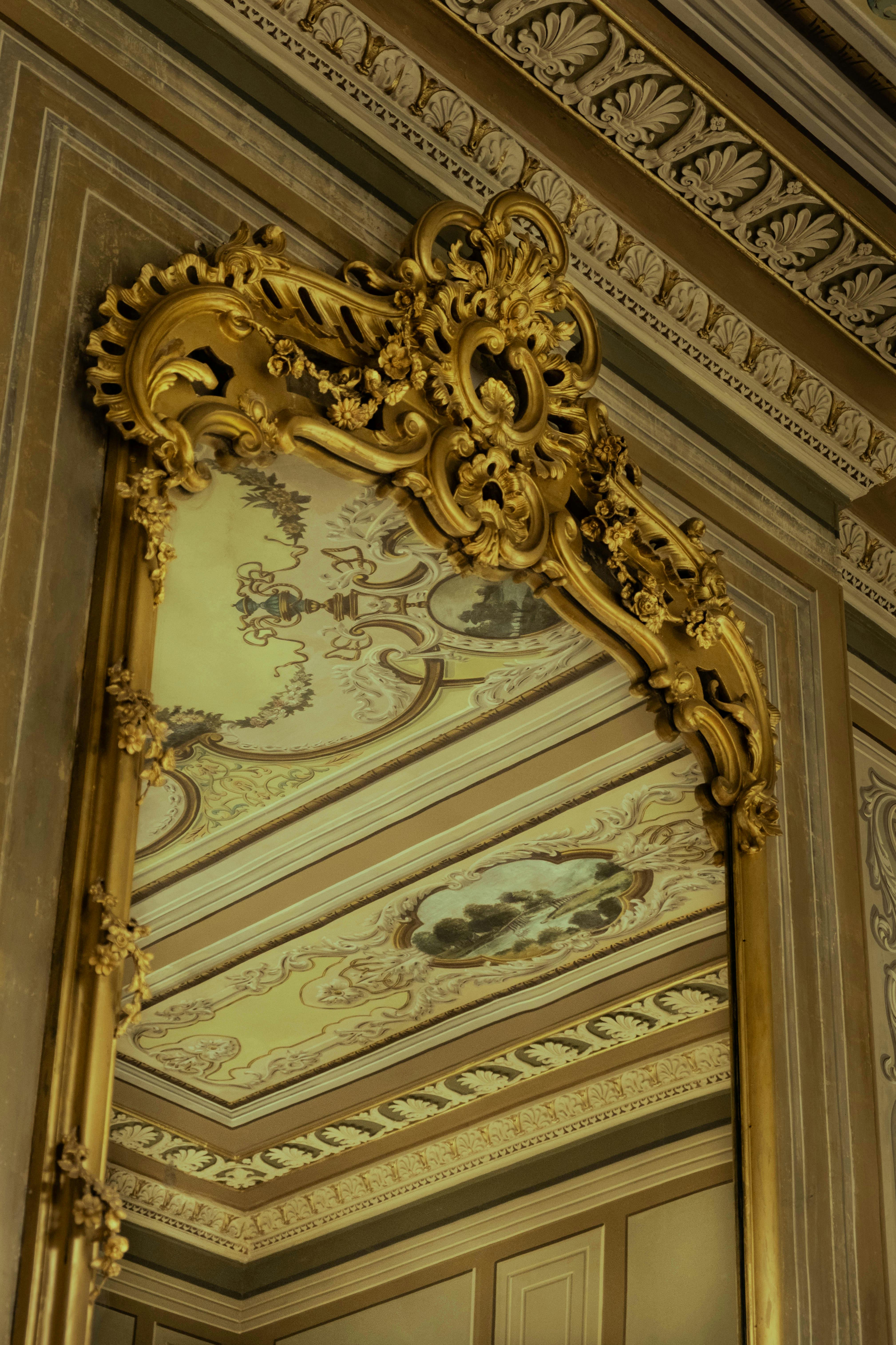Opulent gold Baroque mirror reflecting intricate ceiling design in Istanbul palace.