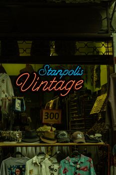 Vintage shop with neon sign and hats on display at night.