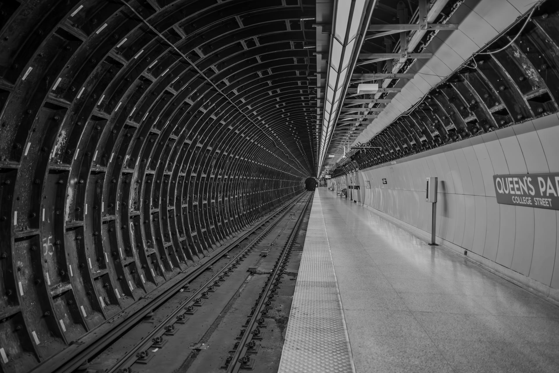 A black and white view of Queen's Park subway station tunnel with no people present.