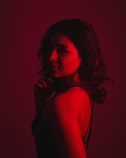 Free Striking portrait of a woman in dramatic red lighting, conveying mystery and allure. Stock Photo