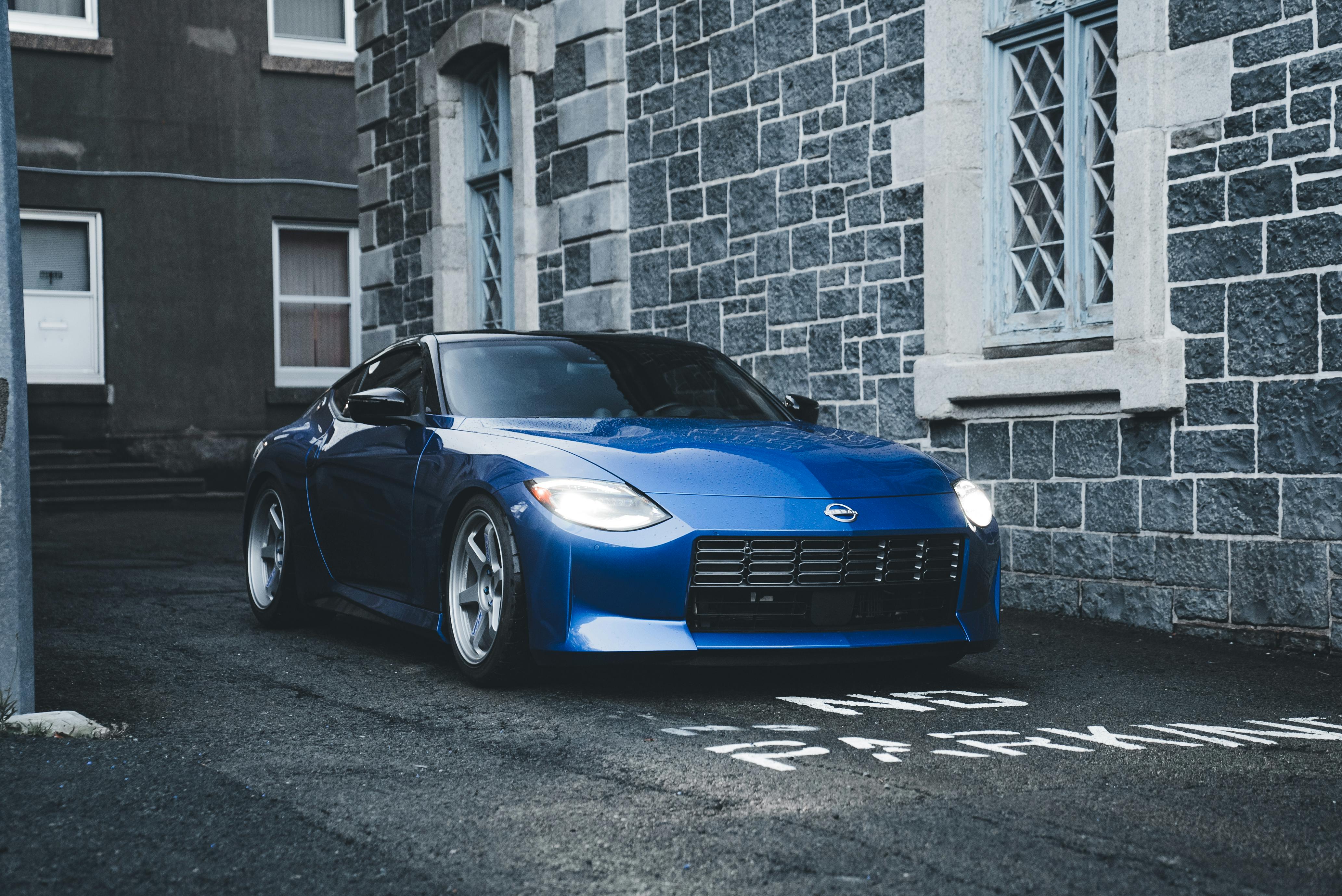 Free Blue sports car parked in a narrow urban alleyway with stone walls and no parking sign. Stock Photo