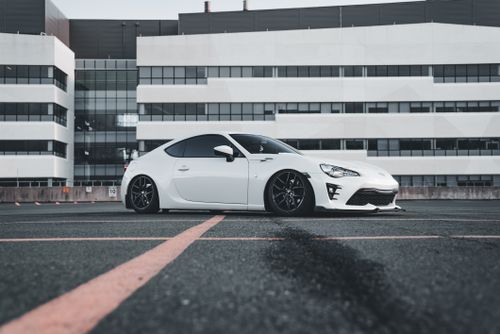 Free White sports car parked in an urban lot, showcasing modern design and style. Stock Photo