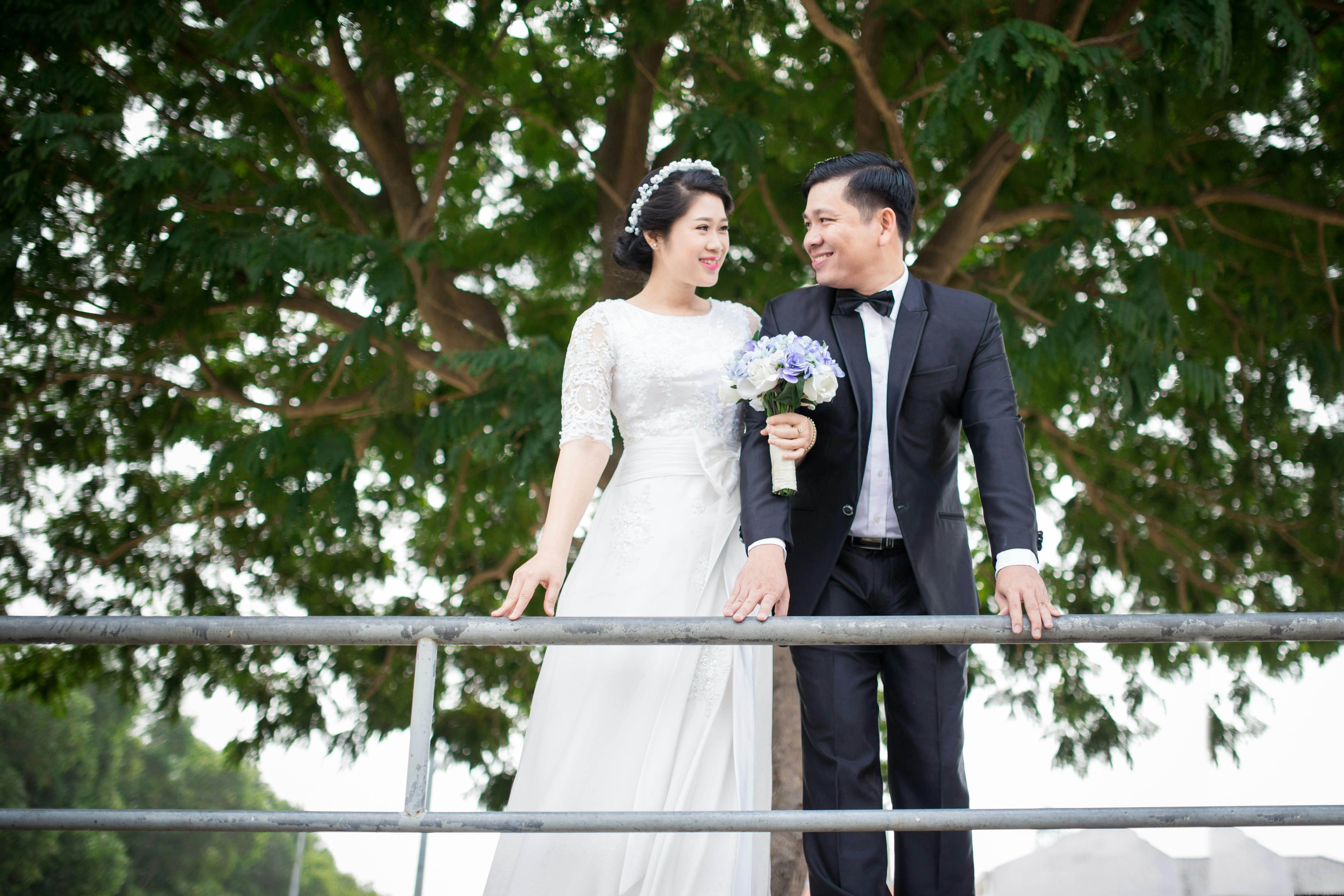 photo of couple smiling while standing near handrail