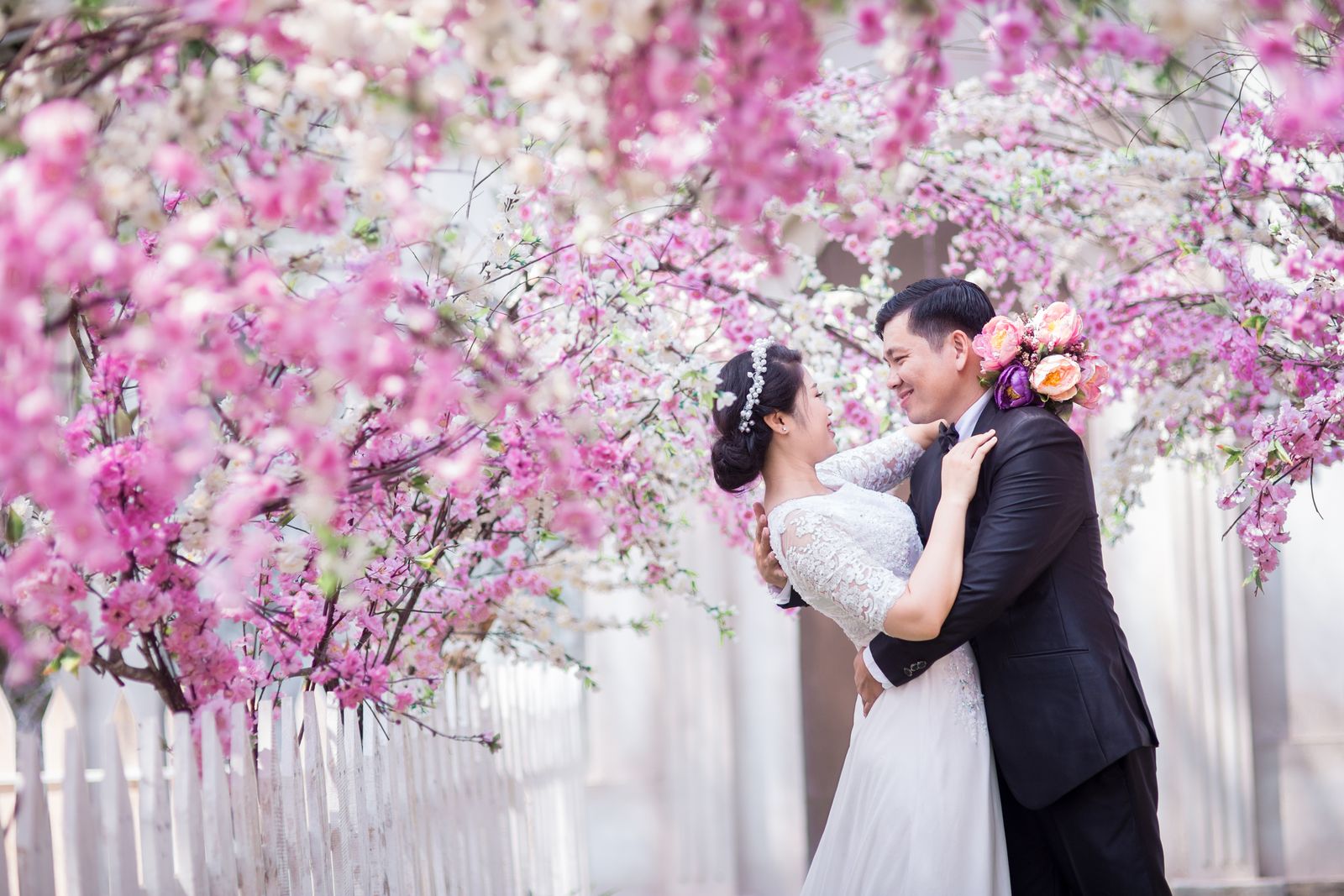 Bride and groom under a pink floral archway at an outdoor spring wedding