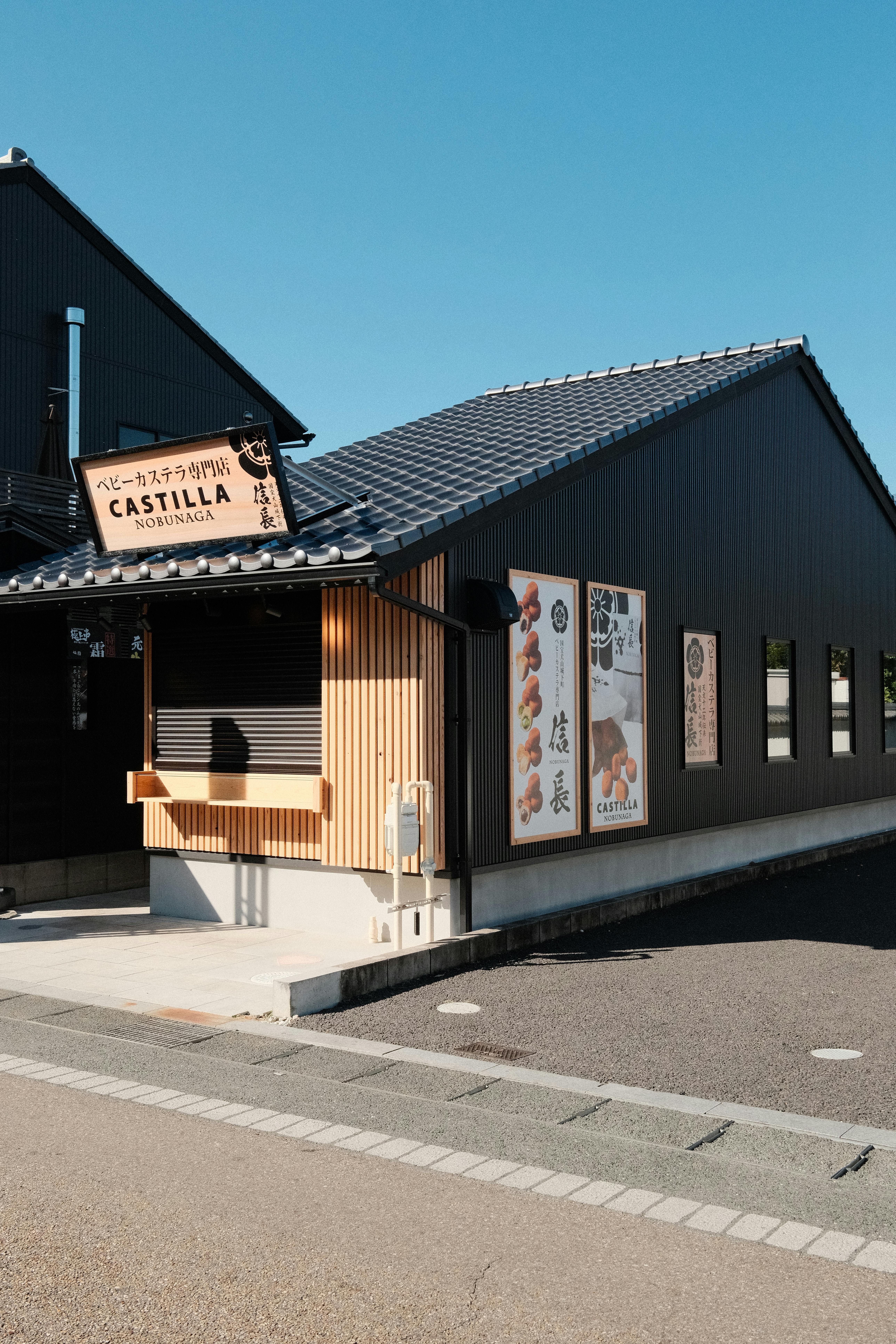 Traditional black tile-roofed building in Inuyama, Aichi, Japan, under blue sky.