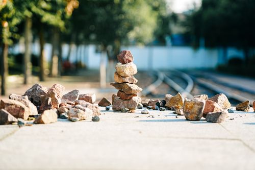 Free A stack of stones on a sidewalk near railway tracks under sunlight. Stock Photo