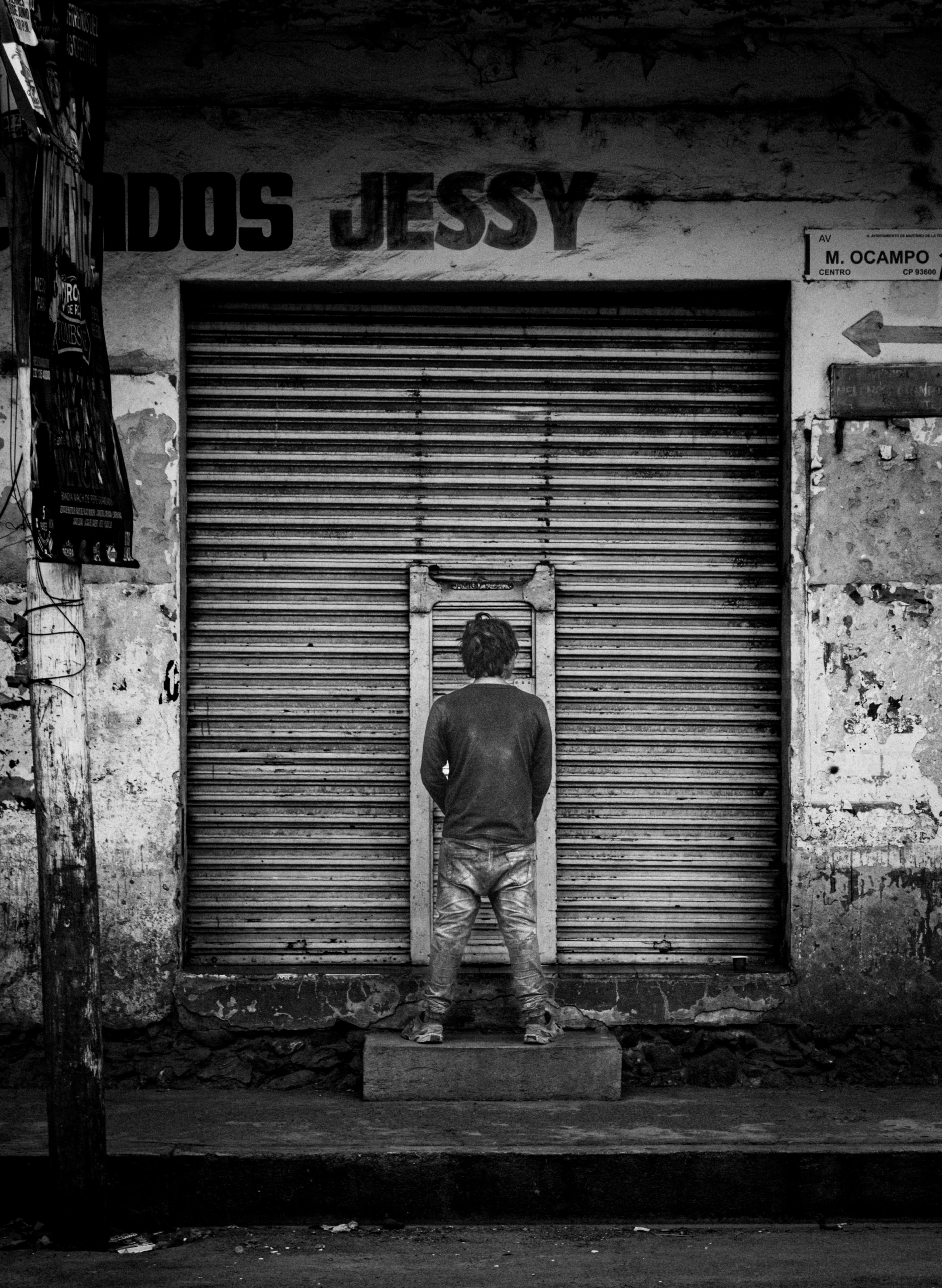 Black and white photo of a child facing a shuttered shop in Martínez de la Torre, Mexico.