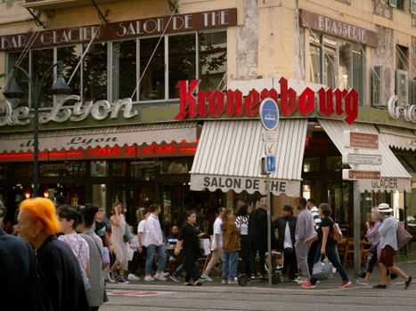 A lively crowd outside a café in France's city center featuring Kronenbourg sign.