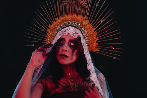 Free Dramatic portrait of a woman in a horror-inspired costume featuring bleeding tears and a halo crown. Stock Photo