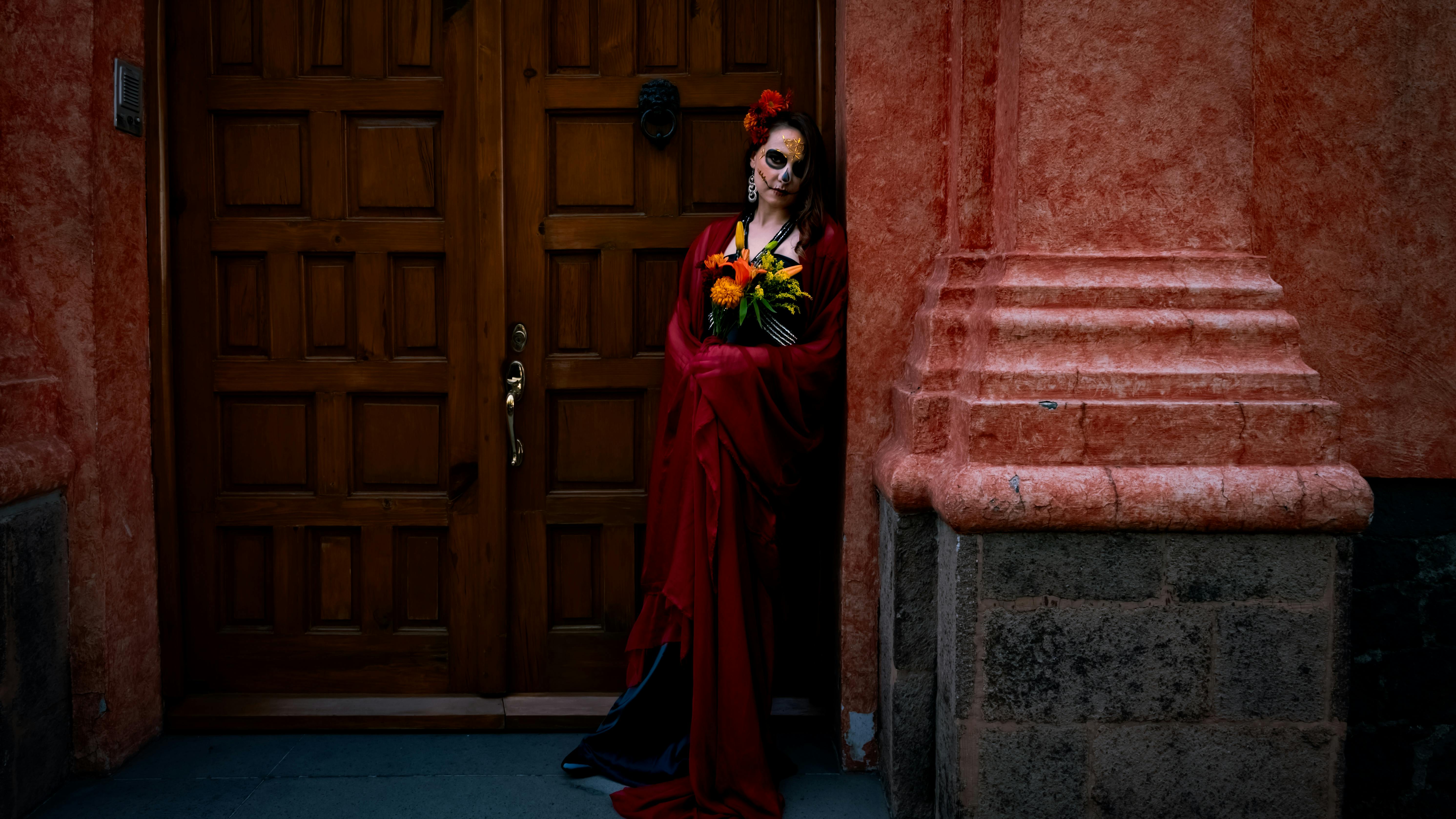 woman in red with calavera face paint by door