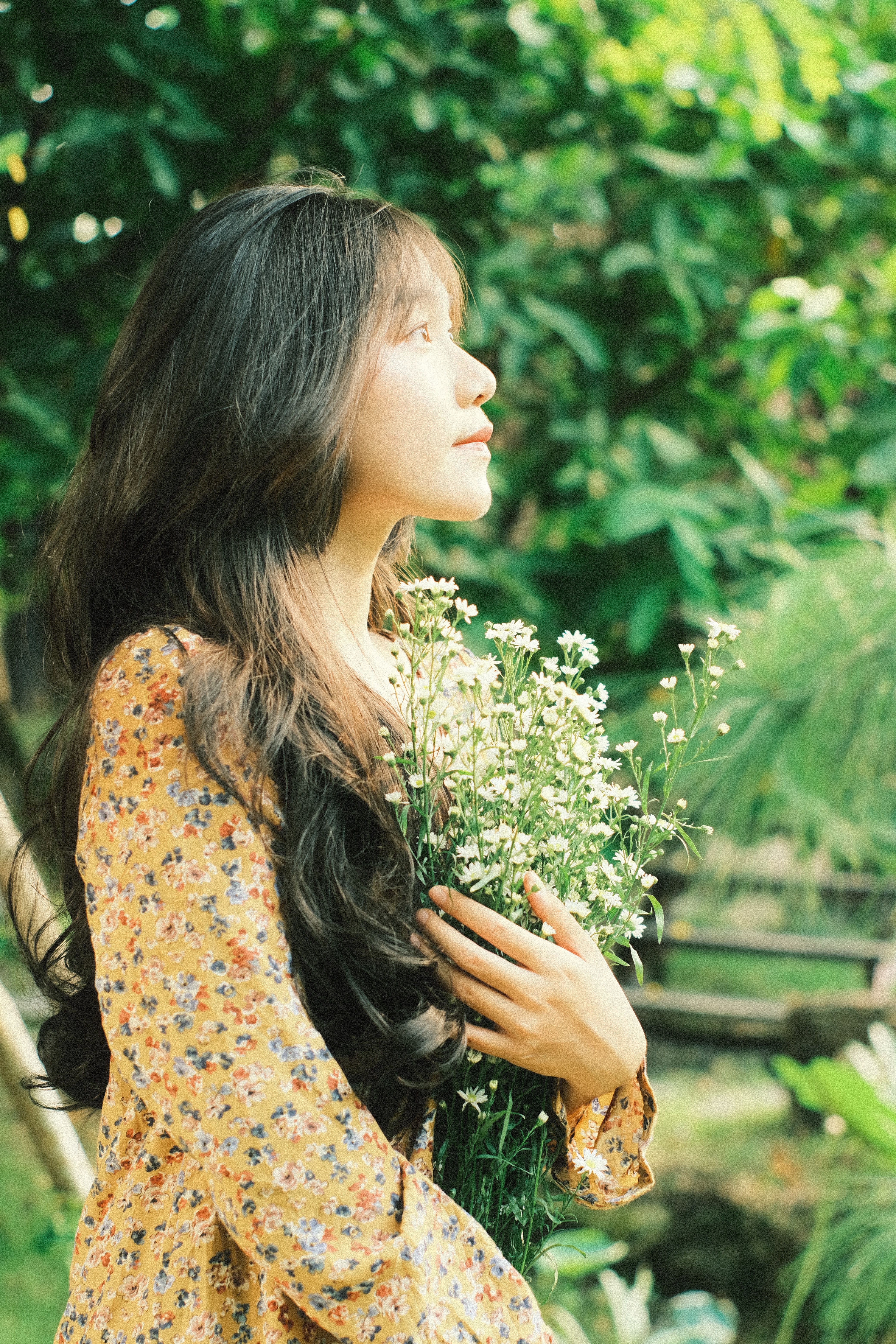 Elegant Woman in Floral Dress Holding Flowers Outdoors · Free Stock Photo
