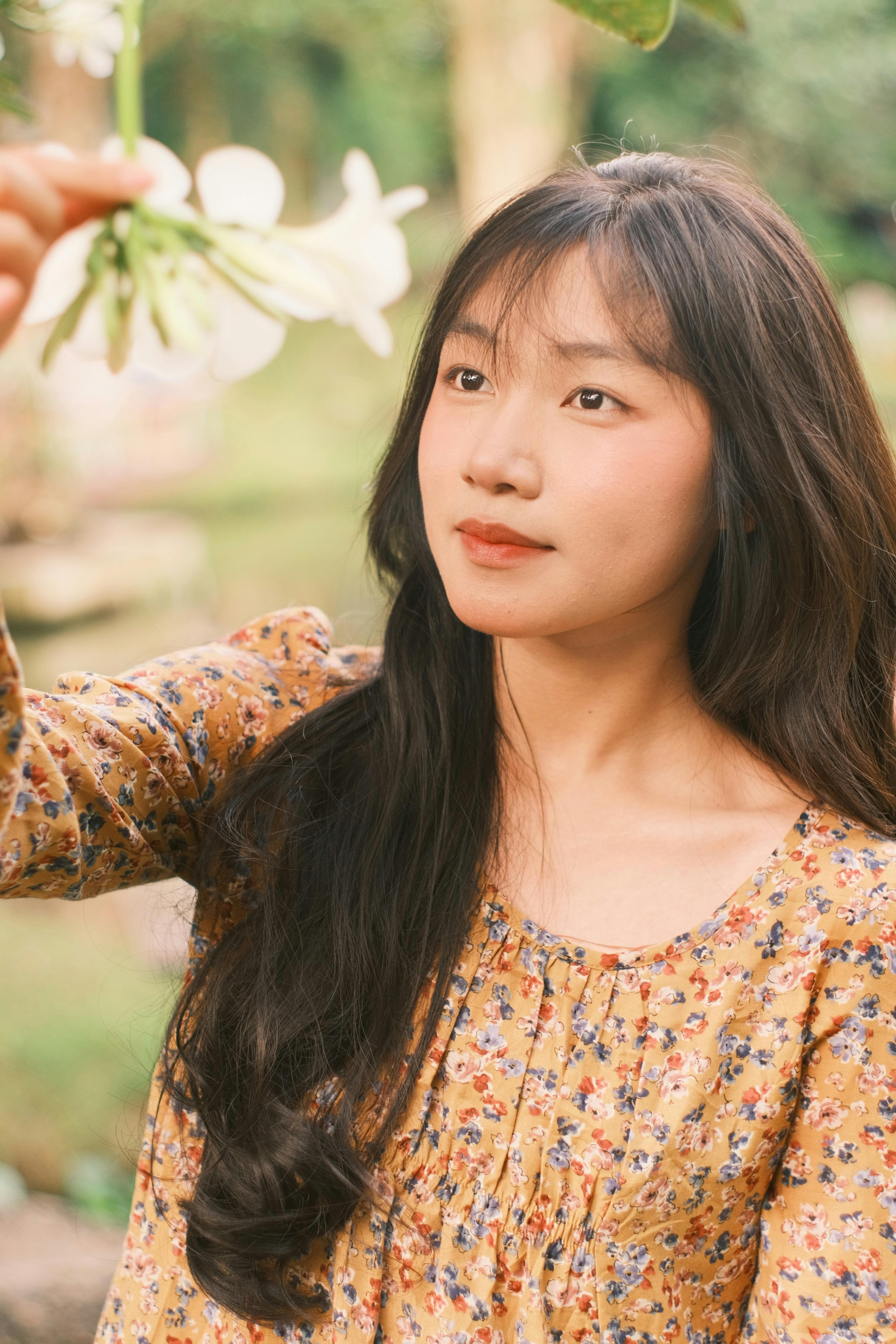 A young woman admiring flowers outdoors, evoking peace and contemplation.