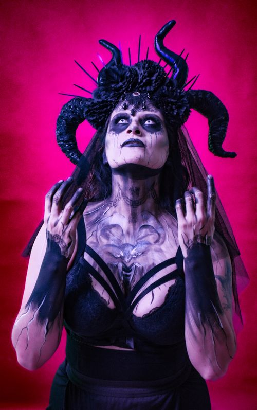 Free Gothic-themed portrait of woman with horned headpiece and intricate face paint against vibrant pink background. Stock Photo