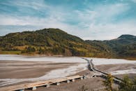 宁静的湖滨，木制步道延伸至蓝天下的郁郁青山