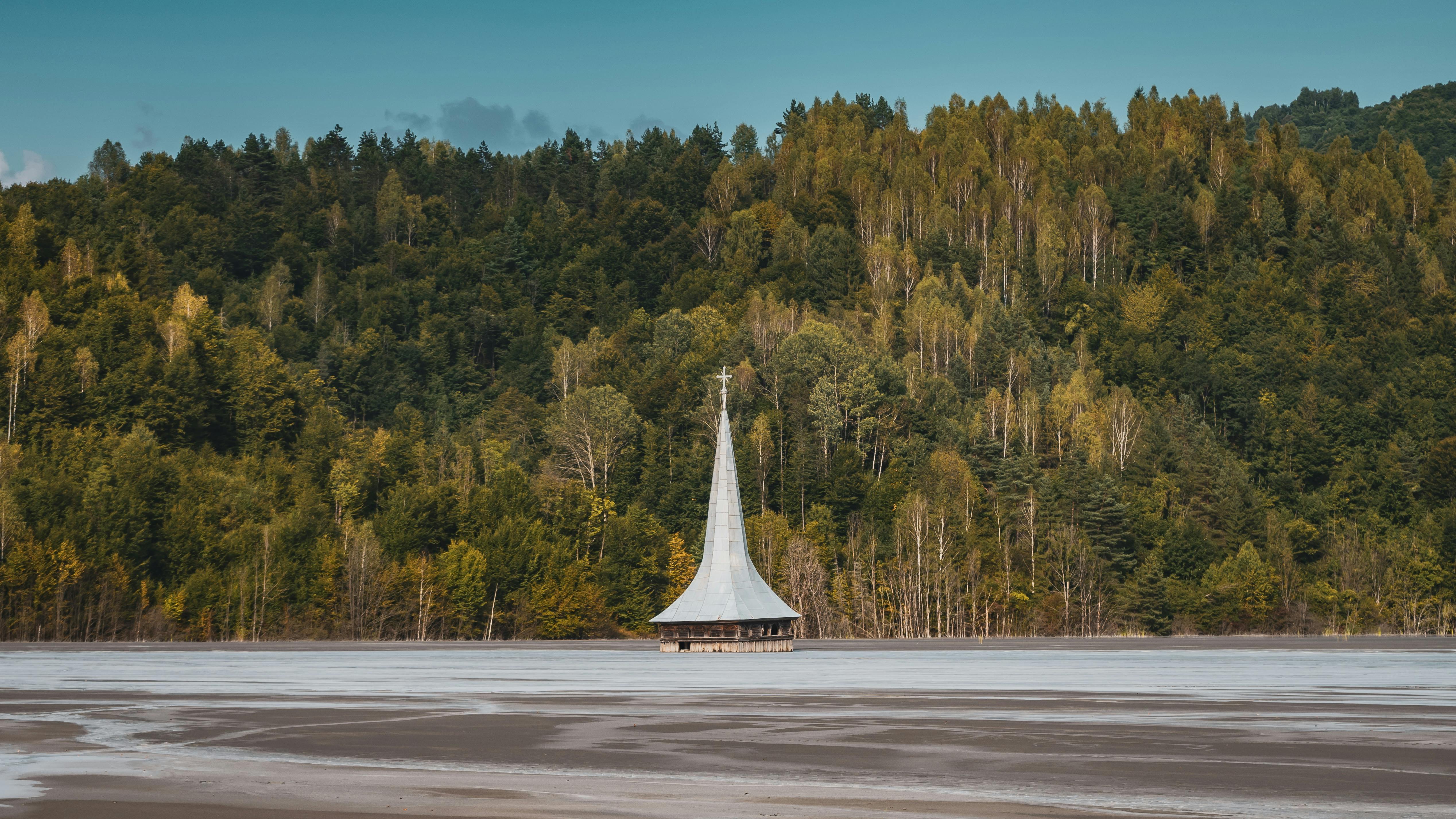 这座风景如画的教堂，四周环绕着郁郁葱葱的森林和宁静的湖泊，照片拍摄于一个阳光明媚的夏日