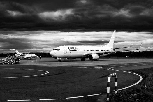 Monochrome image of two airplanes parked at Wrocław airport under dramatic skies.