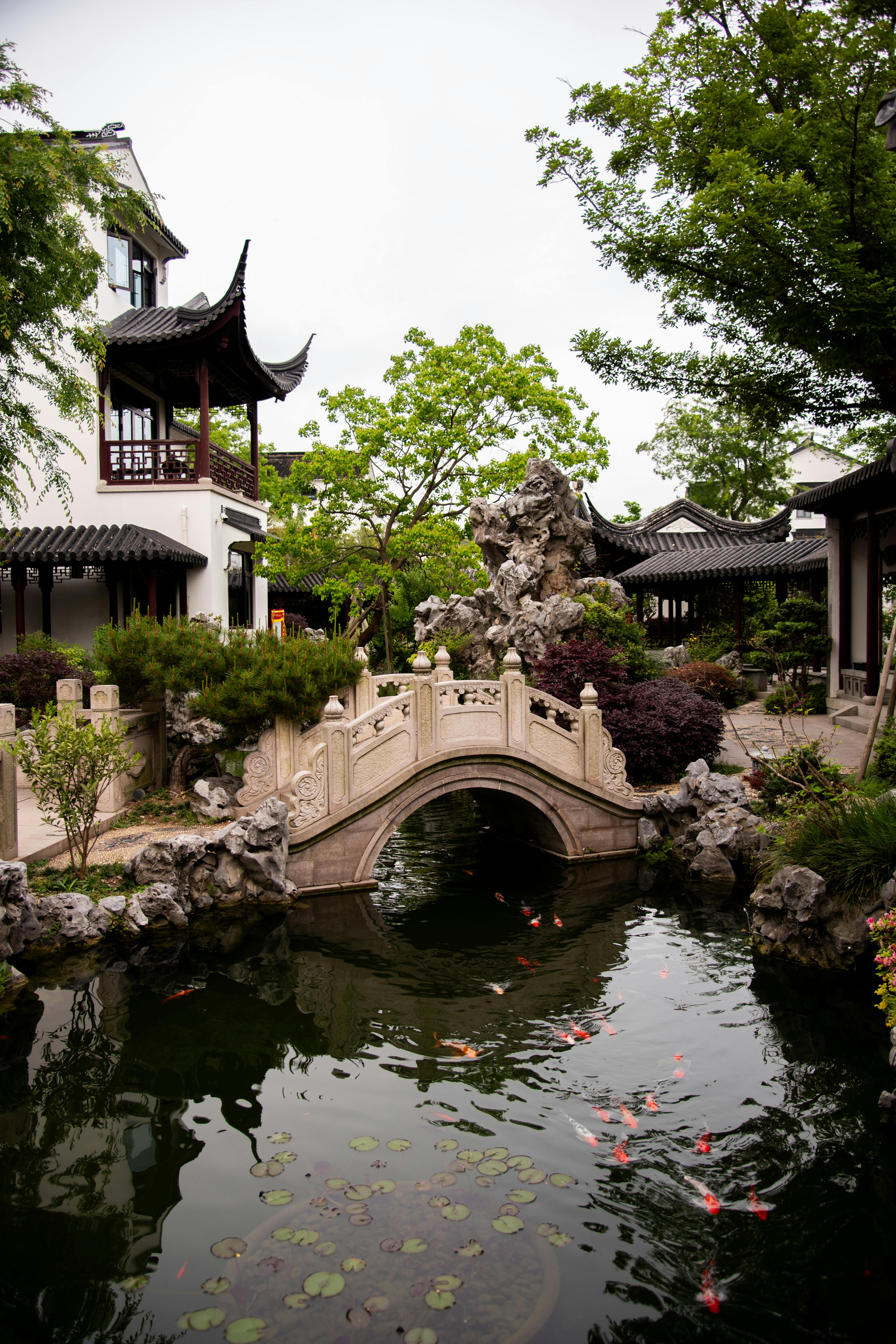 Peaceful view of a traditional Asian garden featuring a stone bridge and koi pond.