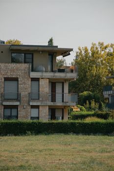 Modern Hungarian apartment building with stone facade and lush greenery on a summer day.