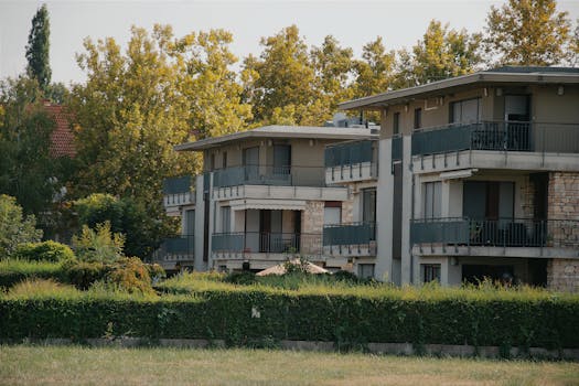 A scenic view of a modern apartment building surrounded by lush greenery in Hungary.