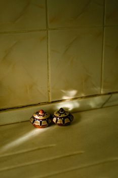 Two decorative ceramic spice jars with sunlight in a kitchen setting.
