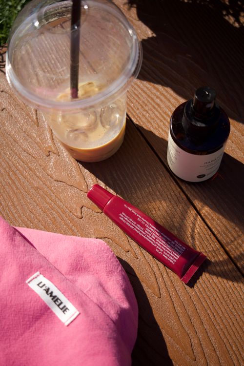 Free Skincare products and iced coffee on wooden table in sunlight. Stock Photo