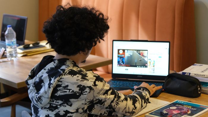 Student studying with headphones and a laptop at a desk
