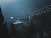 一条蜿蜒的道路风景优美，穿过雾中的山地景观，可见电缆线