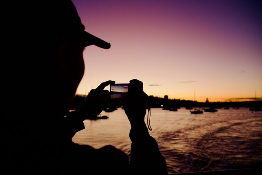 A person takes a photo of a stunning sunset at The Rocks, Sydney.