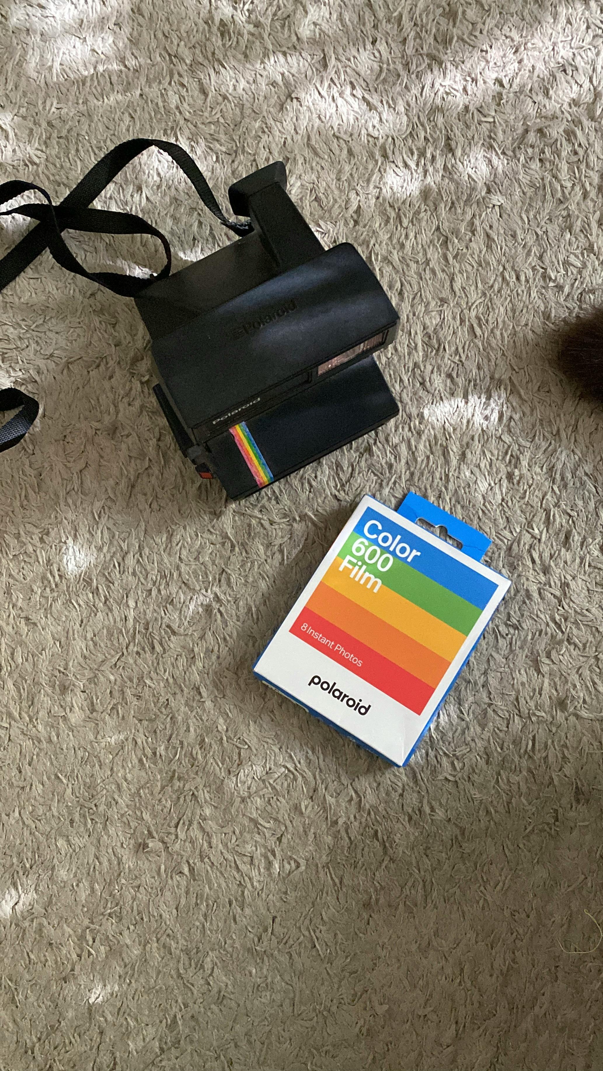 무료 카펫 위의 컬러 필름이 있는 빈티지 폴라로이드 카메라 스톡 사진