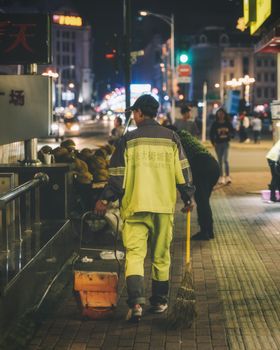 城市清洁工在晚上清扫繁华城市街道的人行道