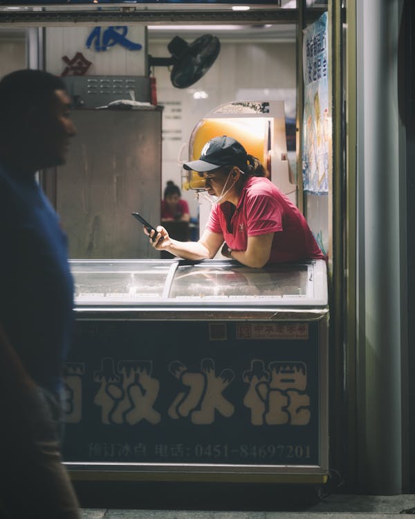 Man Walking in Street Near Woman Leaning on Ice Cream Refrigerator