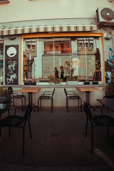 Outdoor café seating area with view inside the cozy café through large windows.