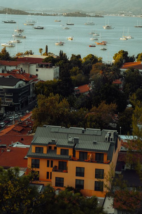 Free Aerial view of a coastal town with boats and colorful rooftops at sunset. Stock Photo