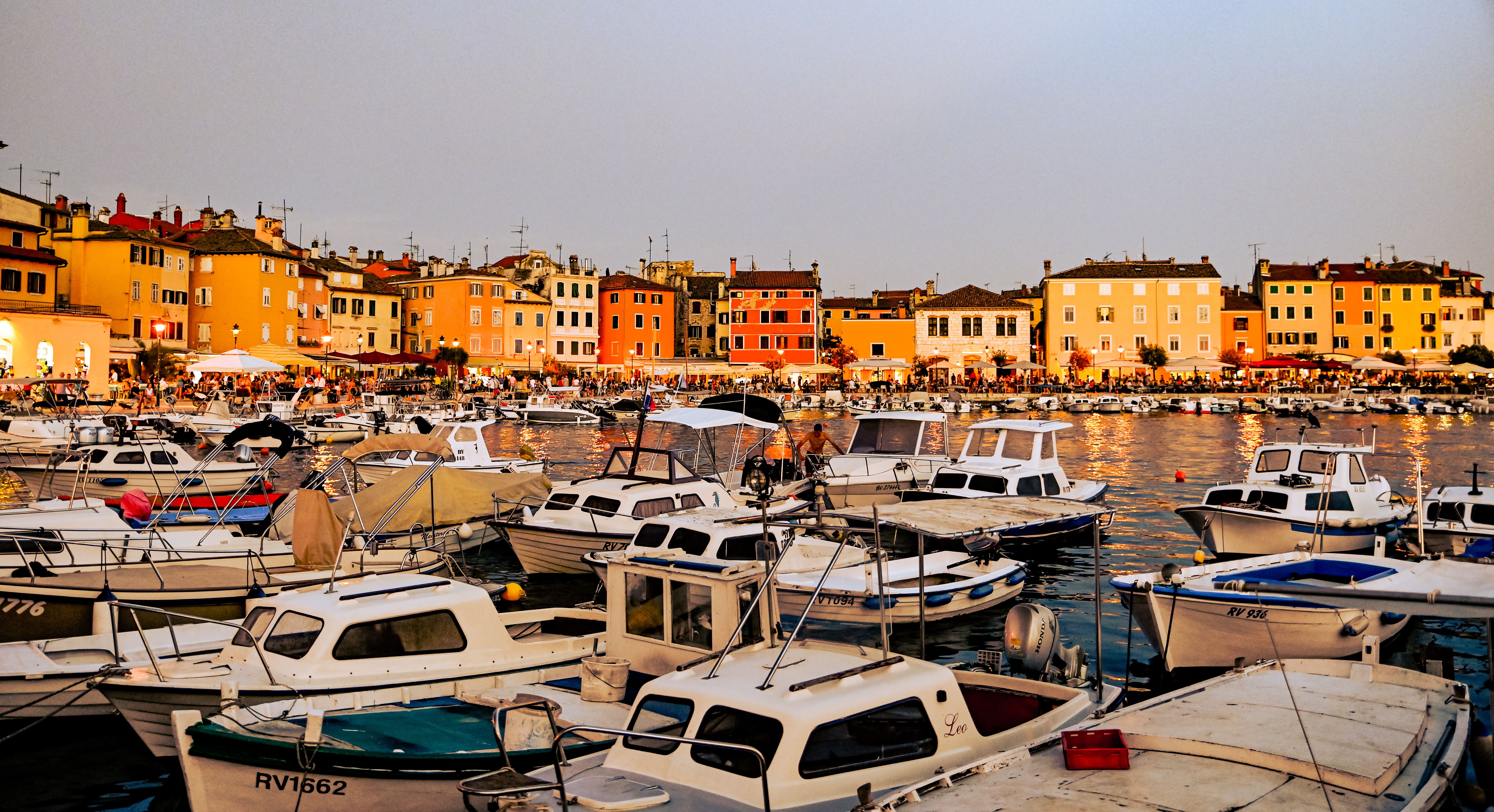 Picturesque view of Rovinj harbor with colorful buildings and boats at sunset.