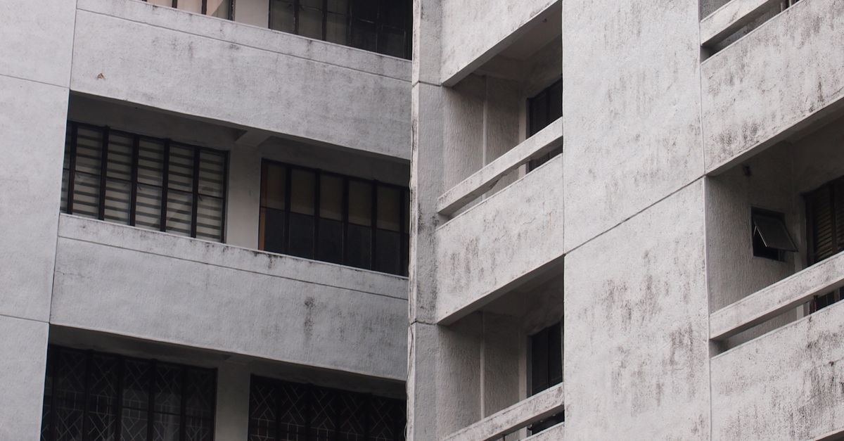 Close-up of a gray concrete apartment building facade with windows.