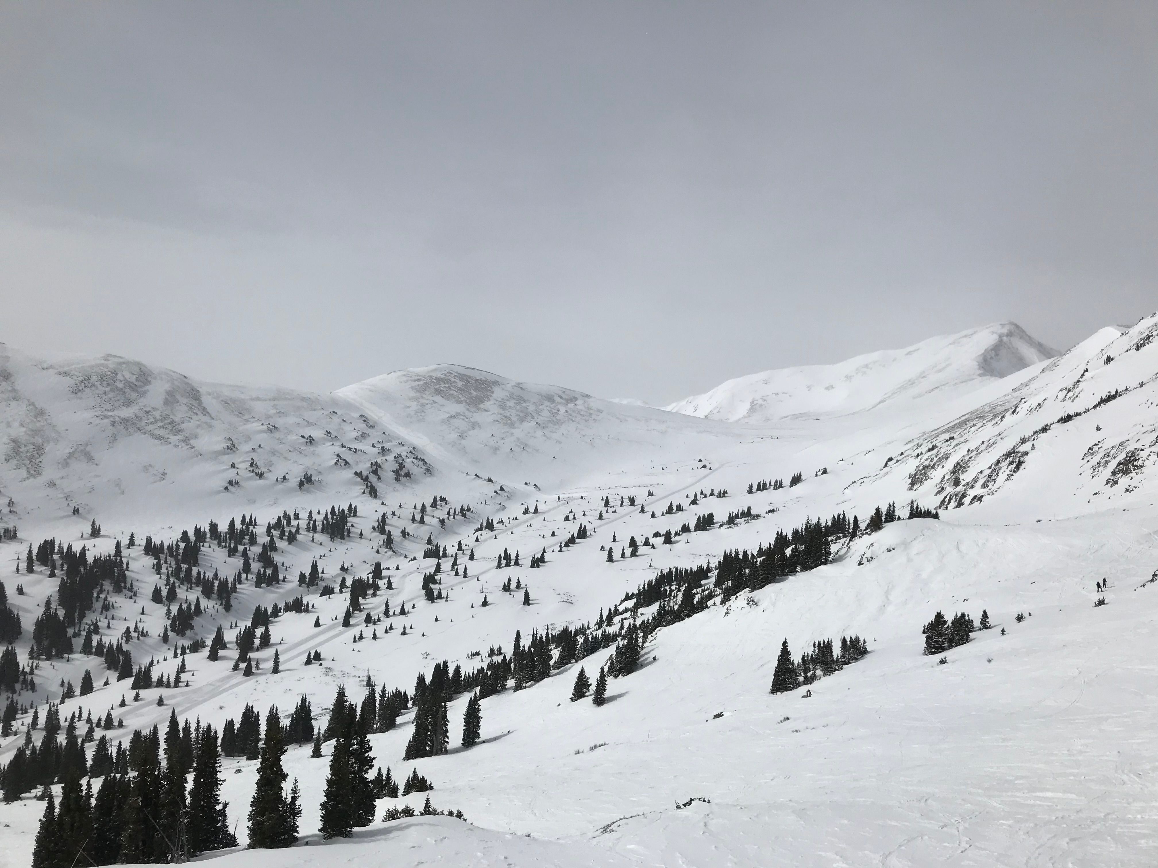 The snow-covered bowls and scattered alpine trees of Copper Mountain, Colorado, under heavy winter cloud
