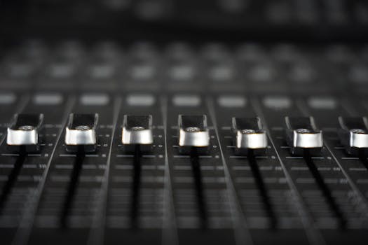 Detailed view of audio mixer faders, essential tool for sound engineering in studios.