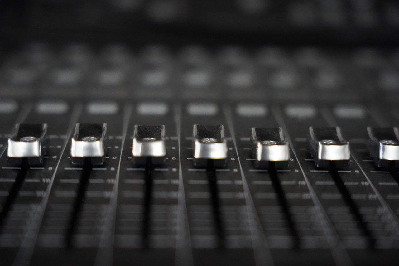 Detailed view of audio mixer faders, essential tool for sound engineering in studios.