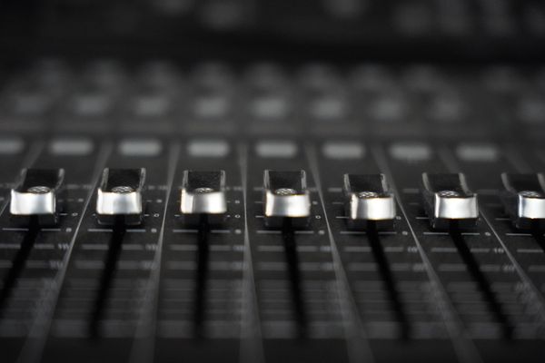 Close-up of faders on an audio mixing console. Photo by David Maat on Pexels.